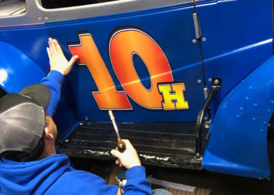 Photo of Steve applying a vinyl decal to a blue race car