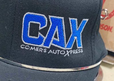 Image showing close-up detail of a custom embroidered hat for Comers Auto Xpress.