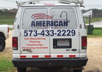 Photograph showing the rear view of a van with vinyl lettering and window perf.