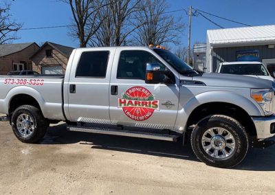 Image of a silver truck with a vinyl door decal and bed lettering for Harris Lawncare and Landscaping.