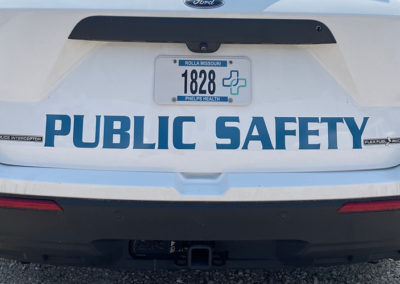 Image of the back of a car with the words "Public Safety" in vinyl letters above the bumper.