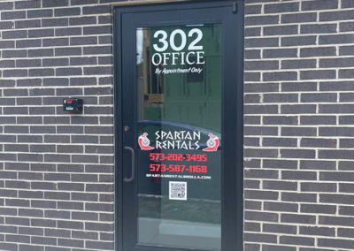 Image of a door window with decals and vinyl lettering for Spartan Rentals.